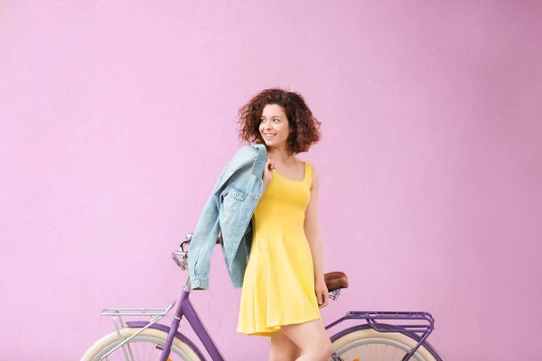 Belle jeune femme avec vélo sur fond de couleur — Photo