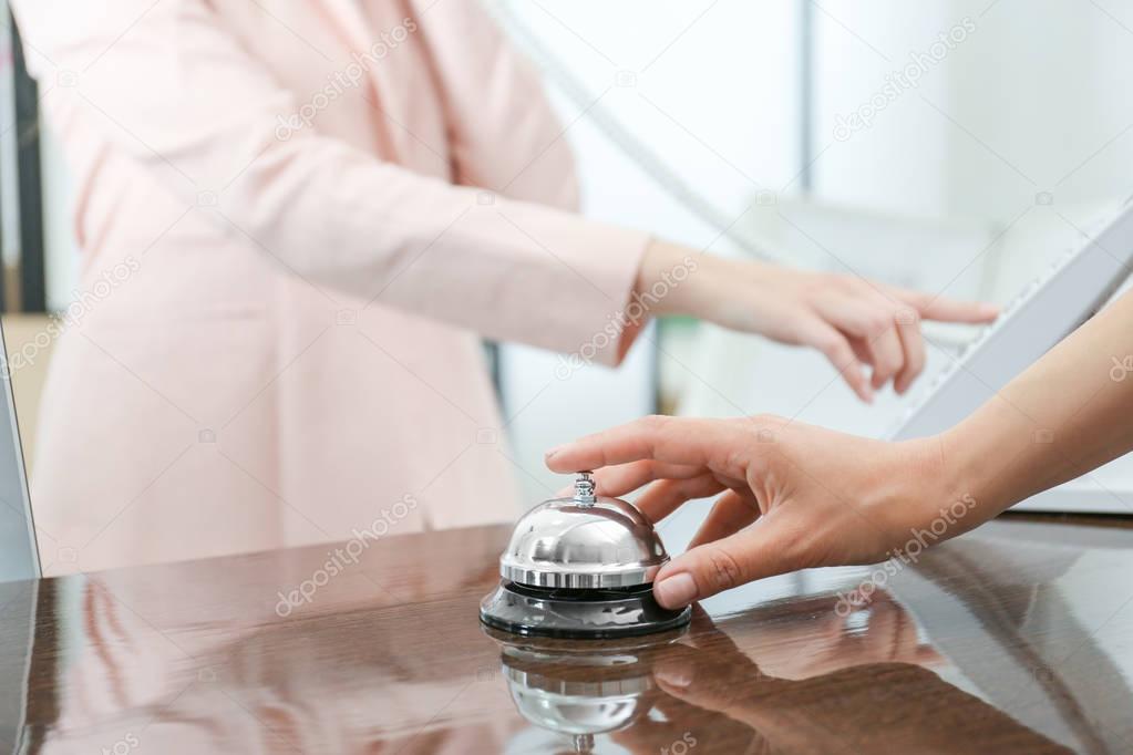 Woman ringing service bell in hotel lobby