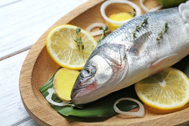 Taze balık ve masada limon dilimleri ile ahşap yemek