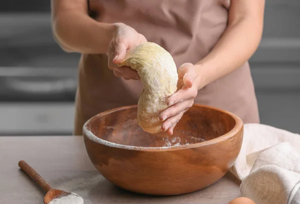 Žena kuchař drží těsto nad mísy na kuchyňském stole — Stock fotografie