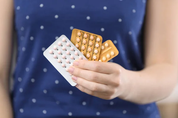 Жінка тримає таблетки контролю народжуваності, крупним планом — стокове фото