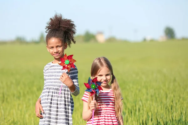 Felice bambine con mulini a vento giocattolo in campo verde — Foto Stock