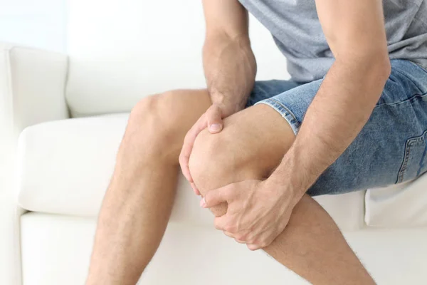 Young man suffering from leg pain at home — Stock Photo, Image