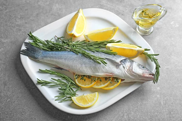 Pescado fresco relleno de romero y rodajas de limón sobre la mesa — Foto de Stock