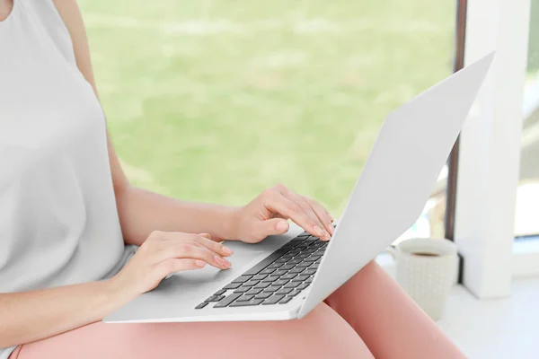 年轻女子在互联网搜索信息，在窗台上使用笔记本电脑 — 图库照片