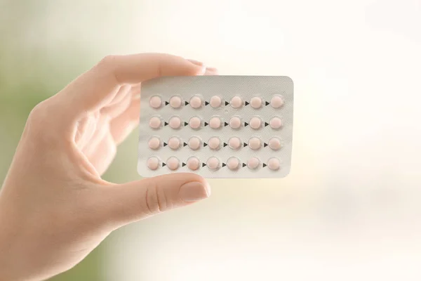 Женская рука с гормональными таблетками на размытом фоне — стоковое фото
