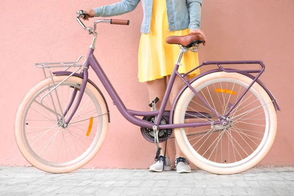 Hermosa mujer joven con bicicleta en fondo de pared de color — Foto de Stock