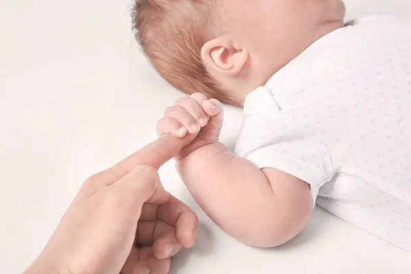 Mignon petit bébé tenant doigt de la mère sur fond blanc — Photo