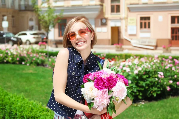 Belle jeune fille avec des fleurs de pivoine en boîte cadeau, en plein air — Photo