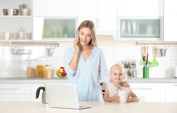 Upptagen ung kvinna med sin dotter hemma — Stockfoto