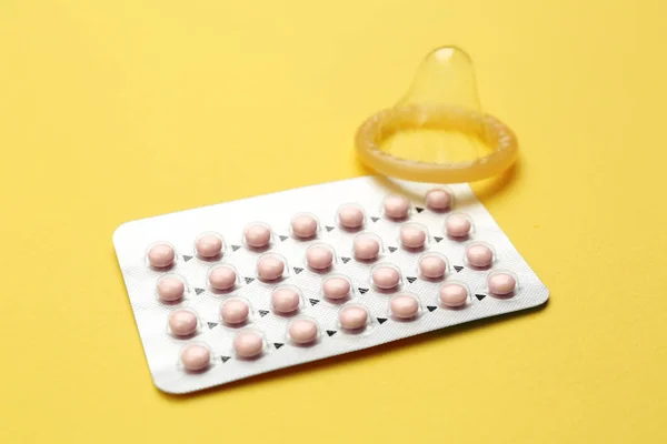 Blistr s antikoncepční pilulky a kondom na barvu pozadí — Stock fotografie