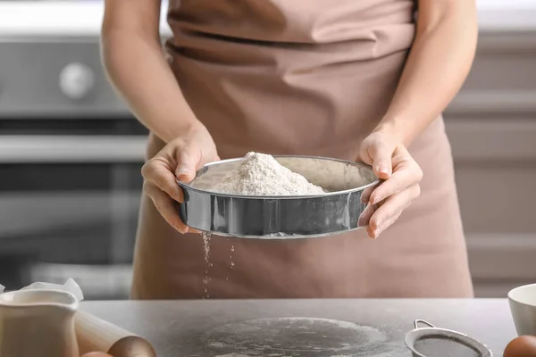 Chef hembra tamizando harina en la mesa de la cocina — Foto de Stock