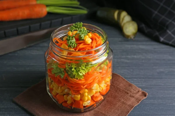 Jar with delicious carrot salad on wooden table — Stock Photo, Image