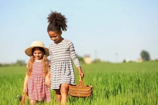 Glückliche kleine Mädchen mit Weidenkörben im grünen Feld — Stockfoto