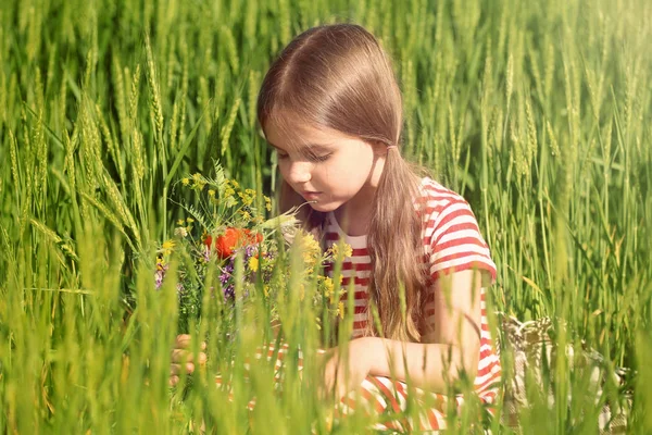 Meisje met boeket van wilde bloemen in groene veld — Stockfoto