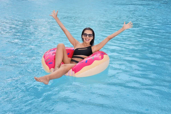 Mooie jonge vrouw op opblaasbare donut in zwembad — Stockfoto