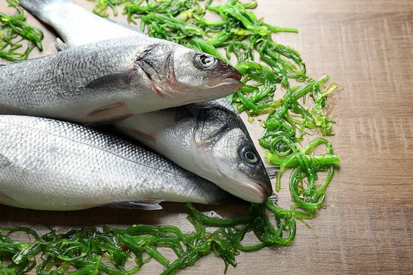 Poisson frais avec salade de chuka sur fond en bois — Photo