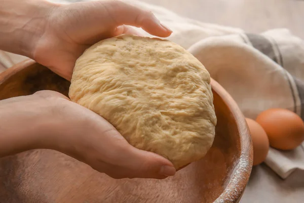 Female chef holding dough over bowl on kitchen table Royalty Free Stock Photos