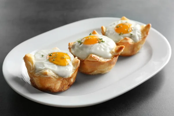 Tasty baked eggs in dough on plate — Stock Photo, Image