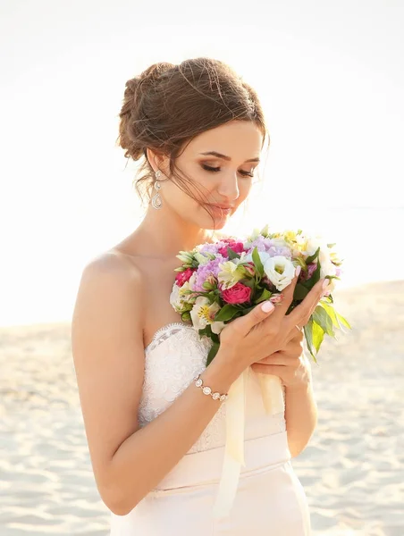 Schöne Braut mit Brautstrauß am Strand — Stockfoto