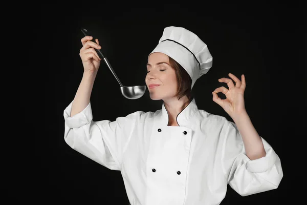 Vrouwelijke chef-kok met pollepel op donkere achtergrond — Stockfoto