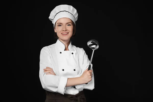 Žena kuchař s naběračkou na tmavém pozadí — Stock fotografie