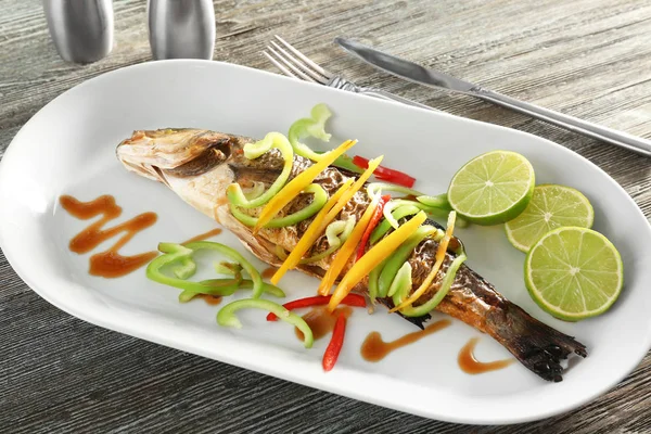 Serving plate with delicious fish in sauce and vegetables