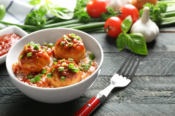 Deliciosas albóndigas con arroz y salsa en un tazón sobre la mesa —  Fotos de Stock