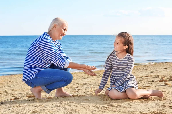 Милая девушка с бабушкой на морском пляже — стоковое фото
