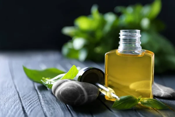 Botella con aceite de albahaca y hojas verdes — Foto de Stock