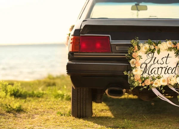 Beautiful wedding car with plate JUST MARRIED on shore — Stock Photo, Image