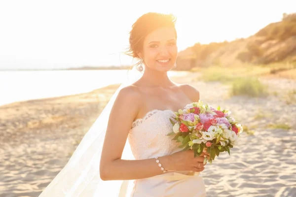 Hermosa novia con ramo de bodas en la playa —  Fotos de Stock