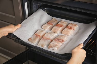 Fırında pişirme balık fileto dilimleri tepsiye koyarak kadın