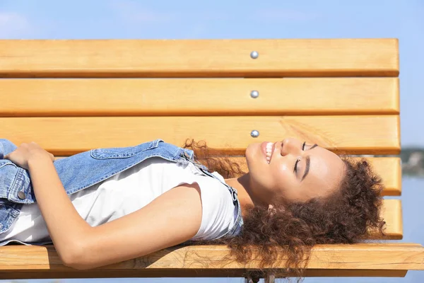 Jeune femme couchée sur un banc en bois à l'extérieur — Photo
