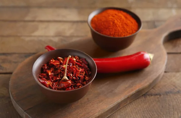 Pó de pimenta, flocos e pimenta crua em tábua de madeira — Fotografia de Stock