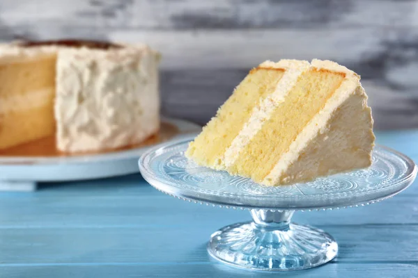 Scheibe leckerer Vanillekuchen auf blauem Holztisch — Stockfoto