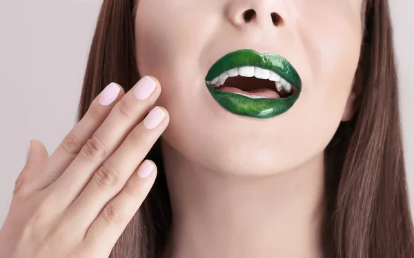 Jeune belle femme avec du rouge à lèvres vert fantaisie sur fond de couleur, gros plan — Photo