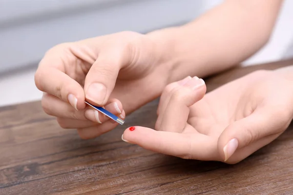 Mulher aplicando gota de sangue na tira de teste dentro de casa — Fotografia de Stock