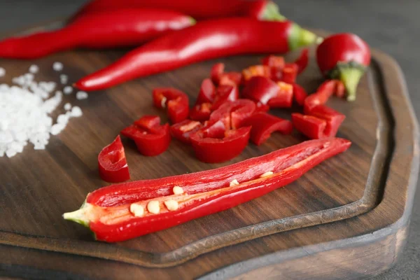 Red chili peppers and sea salt on wooden board, closeup — Stock Photo, Image