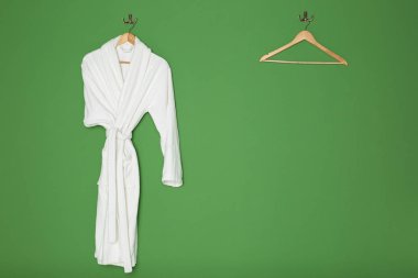 Yeşil renkli ahşap askı ile beyaz bornoz