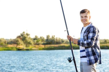Genç adam nehirde balık tutuyor.