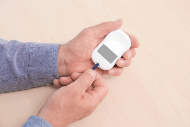 Dijital Şeker Ölçüm ahşap arka plan üzerinde tutan adam