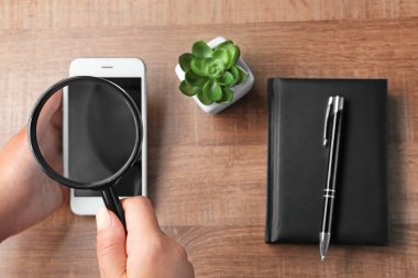 Büyüteç ve akıllı telefon tutan kadın. Internet arama kavramı