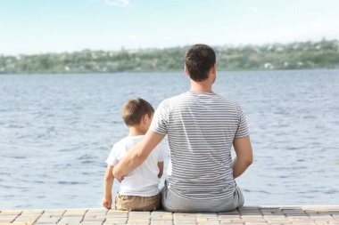 Baba ve oğul iskelede Nehri yakınında oturan