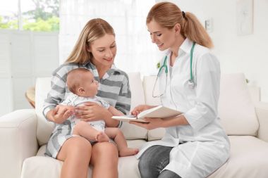 Doktor bir şey defter ve bebek evde annesiyle yazma