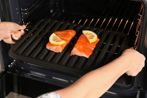 Kvinna att sätta bakplåt med fisk — Stockfoto