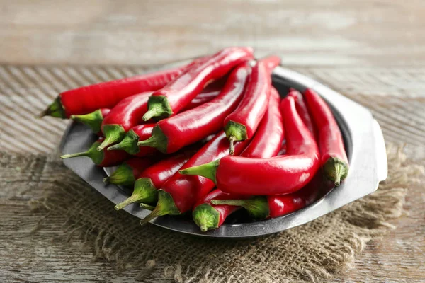 Plate with red chili peppers on wooden table — Stock Photo, Image