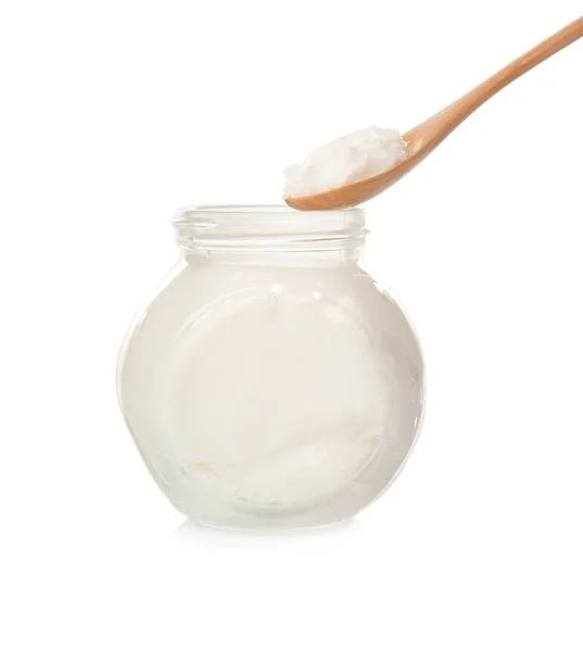 Spoon and jar with coconut oil on white background — Stock Photo, Image