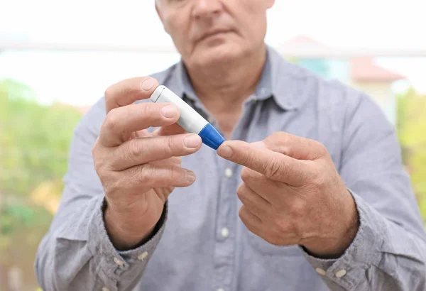 Uomo che preleva campioni di sangue con penna lancet — Foto Stock