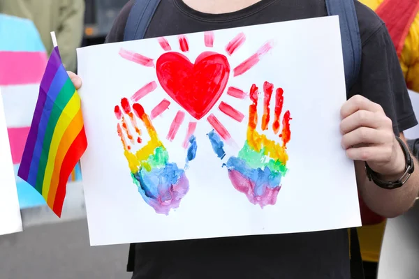Concepto de minoría sexual. Hombre sosteniendo la imagen con las huellas de las manos del arco iris y el corazón al aire libre —  Fotos de Stock